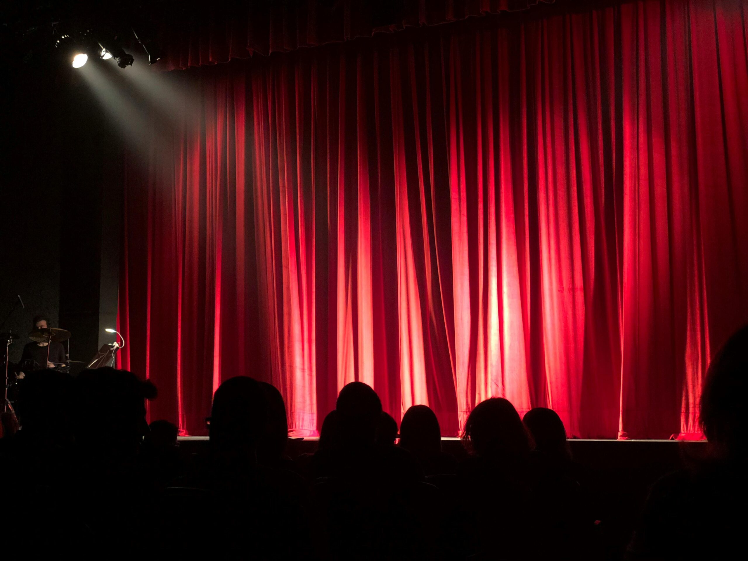 red theater curtain with a spotlight shining on center stage